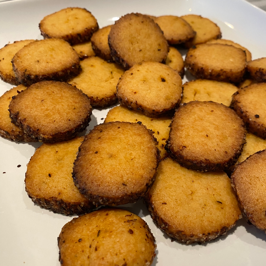A jumble of round yellow cookies rests on a white serving platter. The edges are dark red from Aleppo pepper, and a few of them are a little darker than the others. They still tasted great.